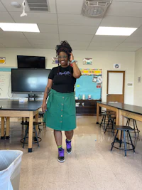 a woman in a green skirt standing in a classroom